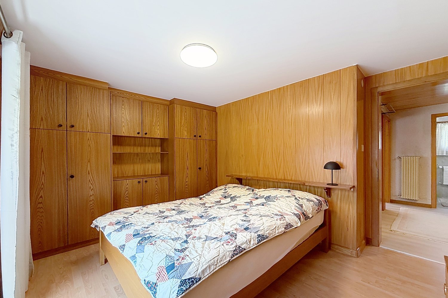 Chambre principale du premier étage avec lit double et armoires encastrées en bois clair.