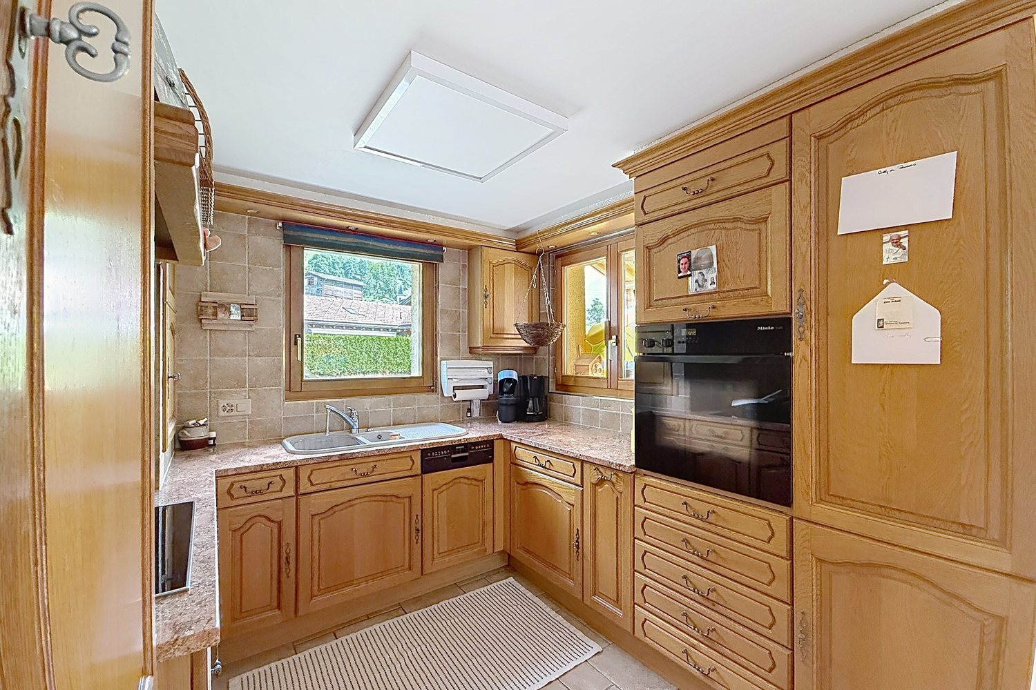 Cuisine séparée du duplex, en bois, avec four encastré et fenêtre sur l'extérieur.