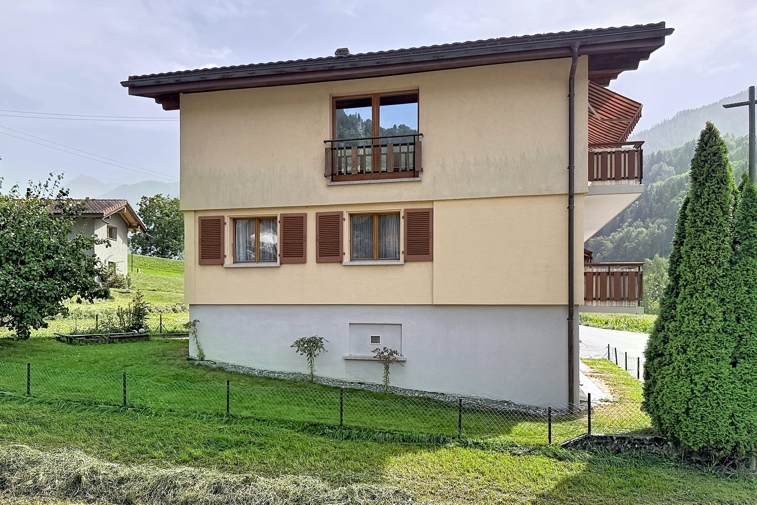 Façade nord-est de la maison : pignon en bois, volets bois et balcons sur le côté est.